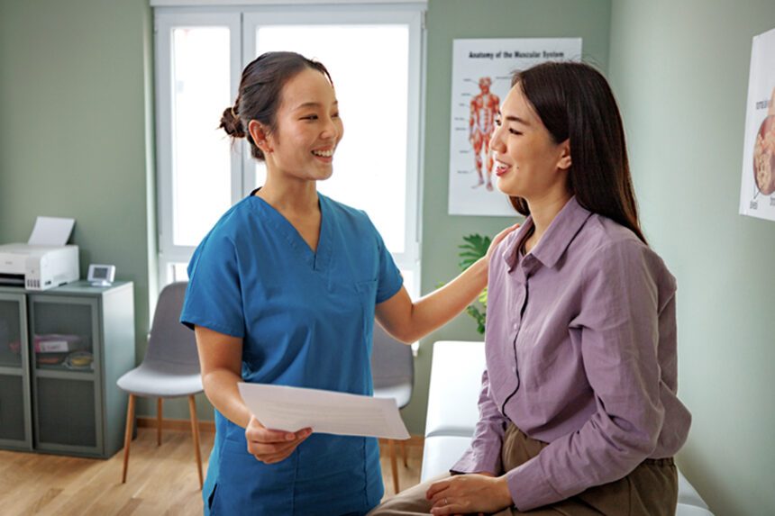 A healthcare professional is having a friendly conversation with a patient during a medical consultation in a clinical setting.