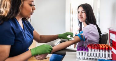 A healthcare professional draws blood from a patient in a medical office.