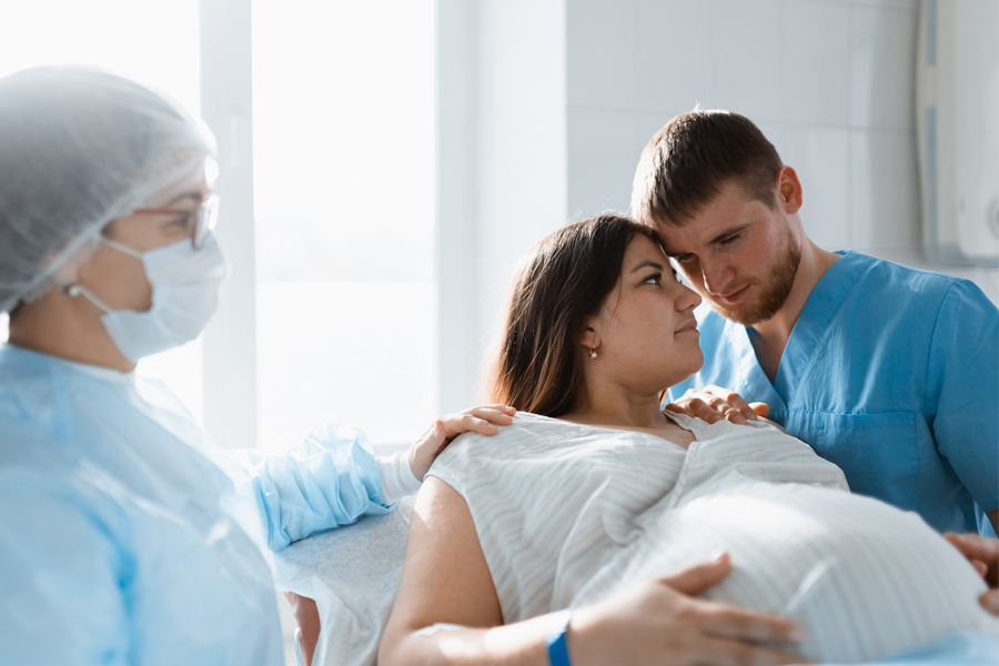 A pregnant woman receives support from a doctor and her partner during labor in a hospital.