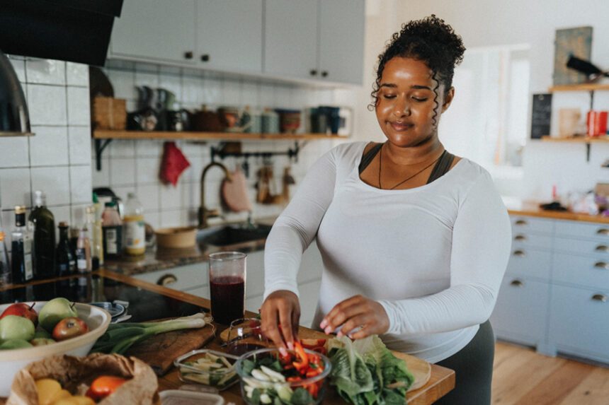 Woman preparing a fresh salad in her kitchen.