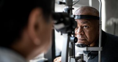 A man undergoes an eye exam with an ophthalmologist using specialized equipment to check the health of his eyes.