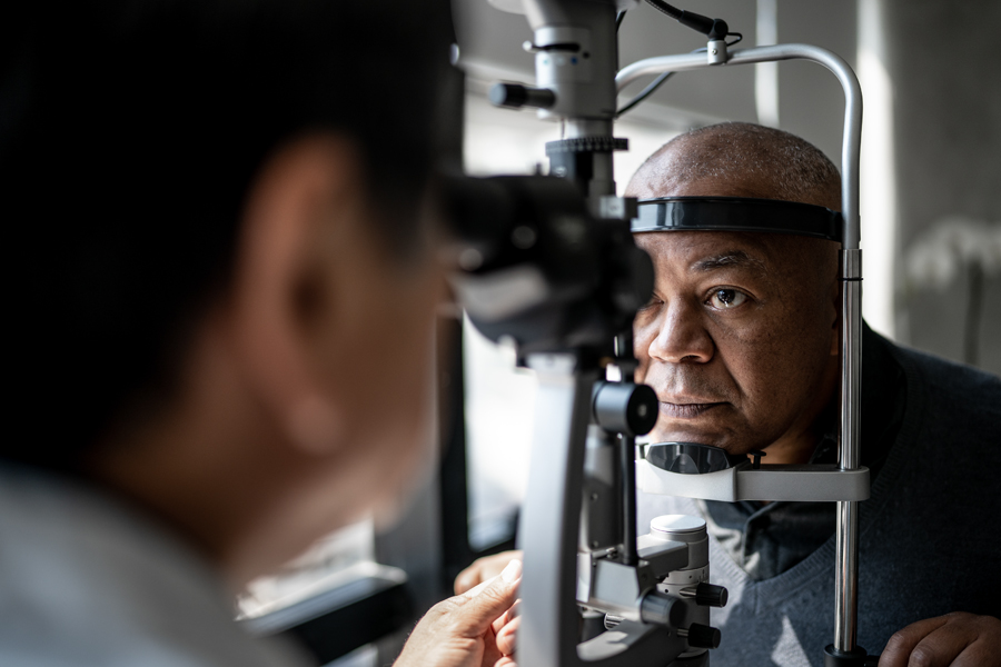 A man undergoes an eye exam with an ophthalmologist using specialized equipment to check the health of his eyes.