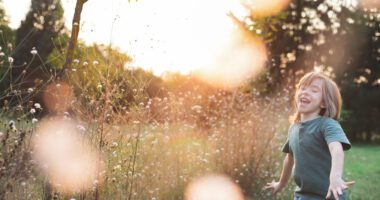 A child runs joyfully through a field at sunset.