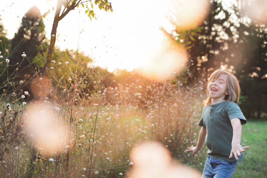 A child runs joyfully through a field at sunset.