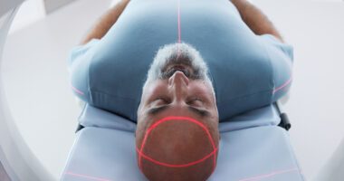 Man lays on exam table, entering CT machine