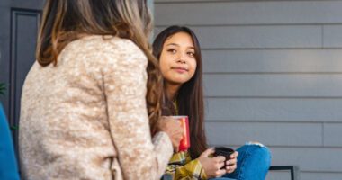 Mom and pre-teen daughter sit on porch, talking