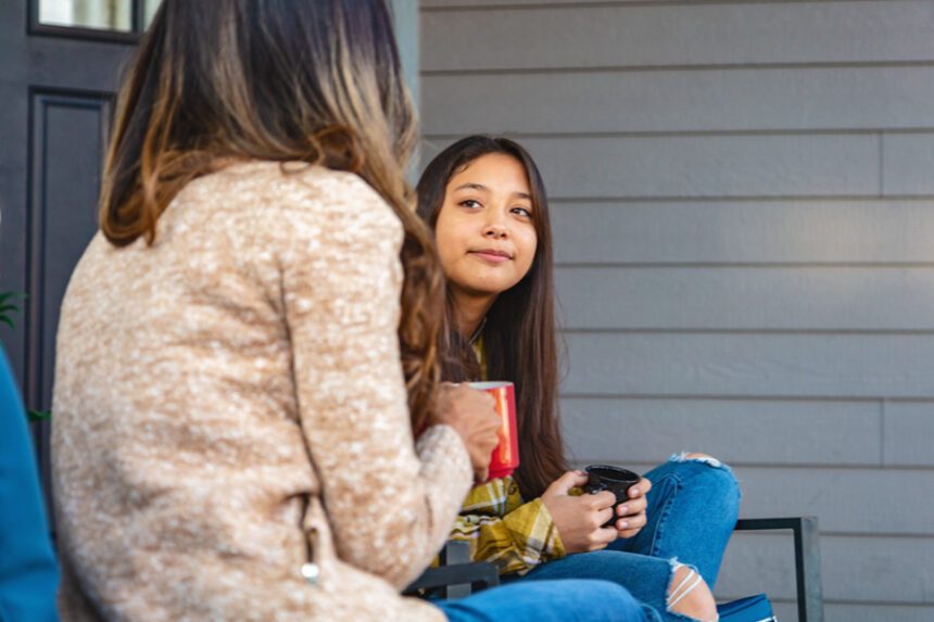 Mom and pre-teen daughter sit on porch, talking