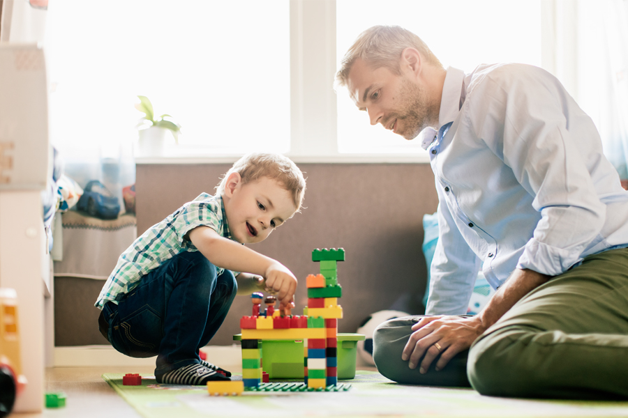 ChatGPT said: An adult man and a young boy build a colorful block tower together on the floor, enjoying a moment of play and learning at home.