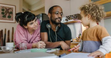 ChatGPT said: A family shares a moment at the table as the parents listen to and support their young child while they draw.