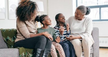 Three generations of a family share a joyful conversation together at home.