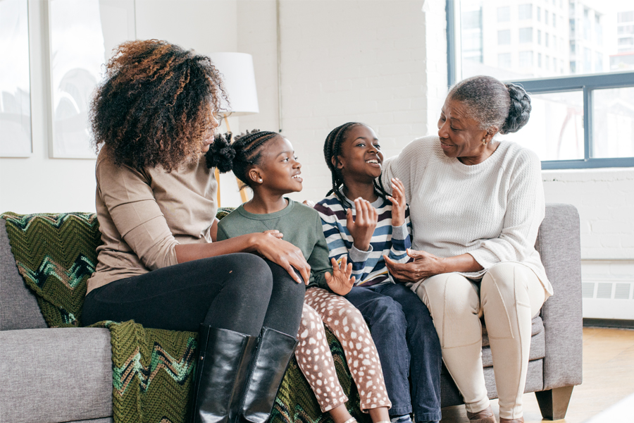 Three generations of a family share a joyful conversation together at home.