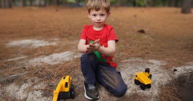 James playing happily with his toy trucks at the park.