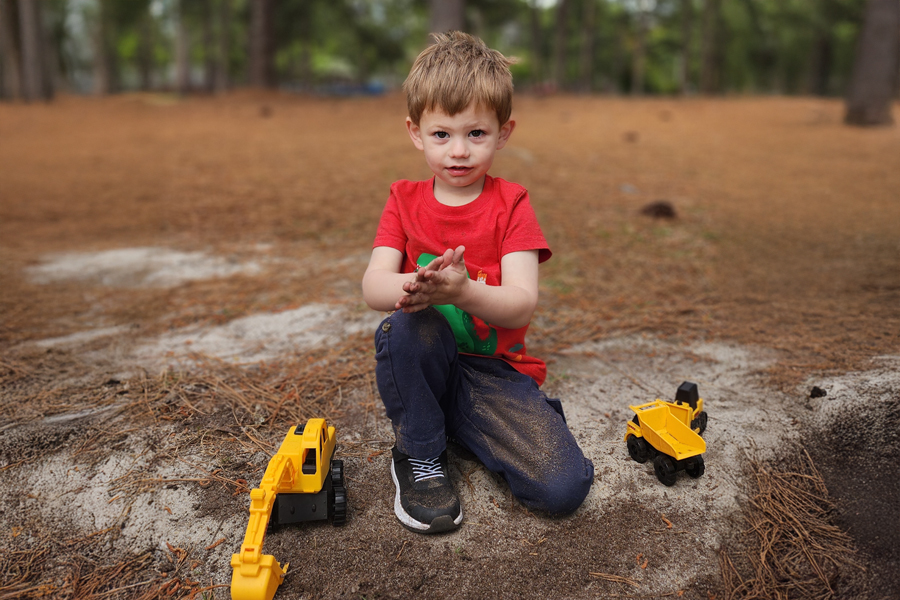 James playing happily with his toy trucks at the park.