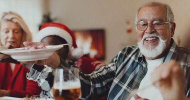 Smiling older man sharing food during a holiday meal.