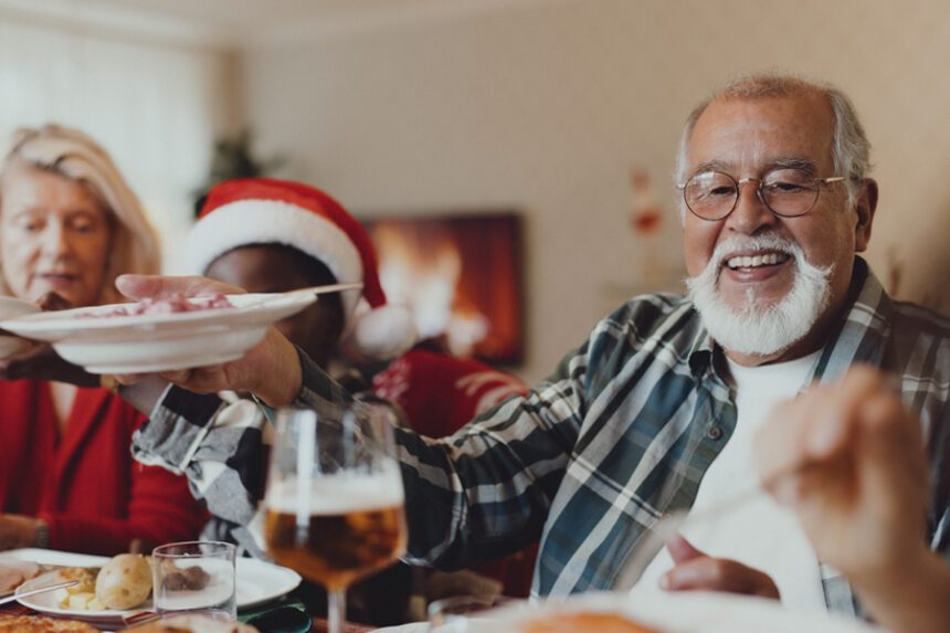Smiling older man sharing food during a holiday meal.