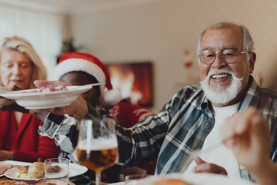 Smiling older man sharing food during a holiday meal.