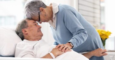 A patient in a hospital bed shares a tender moment with a loved one.