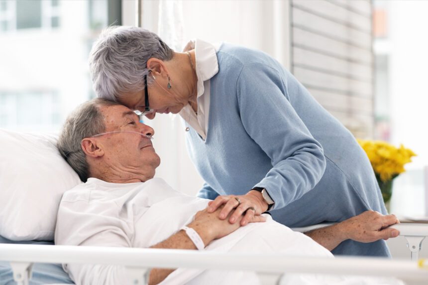 A patient in a hospital bed shares a tender moment with a loved one.