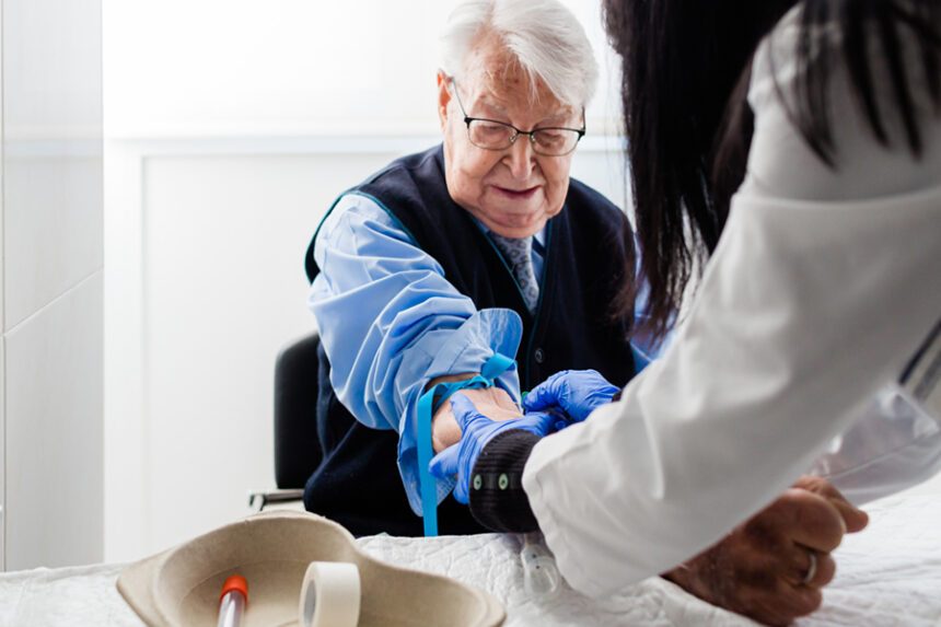 An adult patient seated while a nurse draws blood.