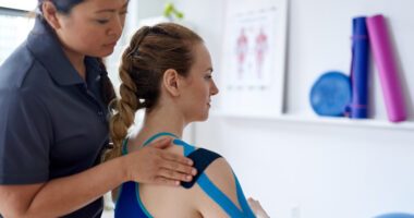 Physical therapist puts tape on a patient's shoulder