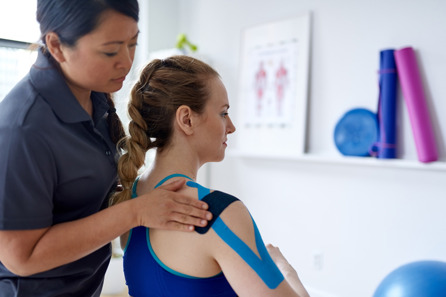 Physical therapist puts tape on a patient's shoulder