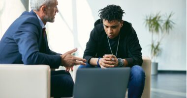 A therapist talking with a young man who looks concerned.