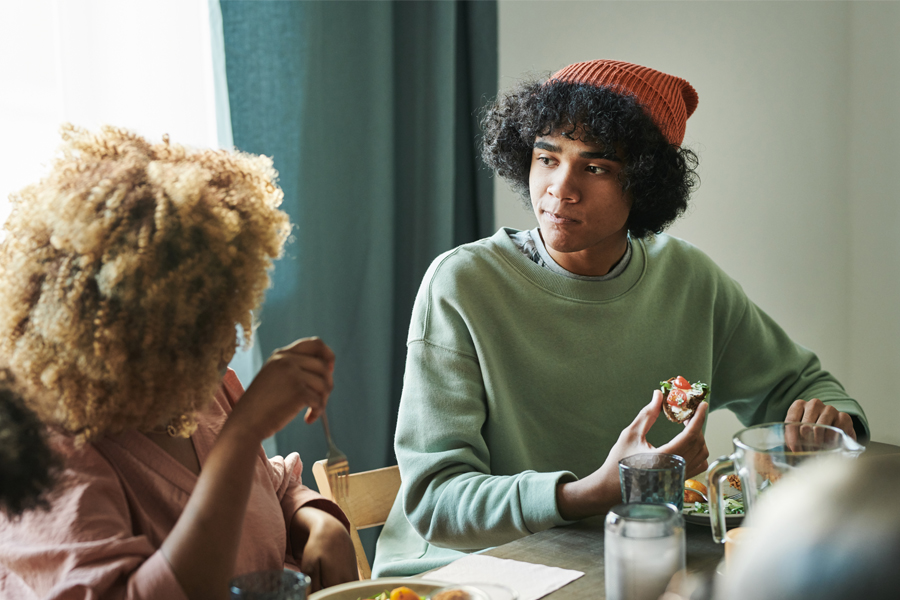mom and teen son talk at the kitchen table