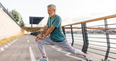 Man with gray hair stretches on a running track