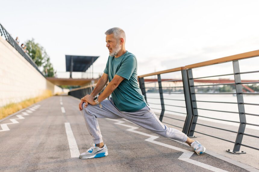 Man with gray hair stretches on a running track