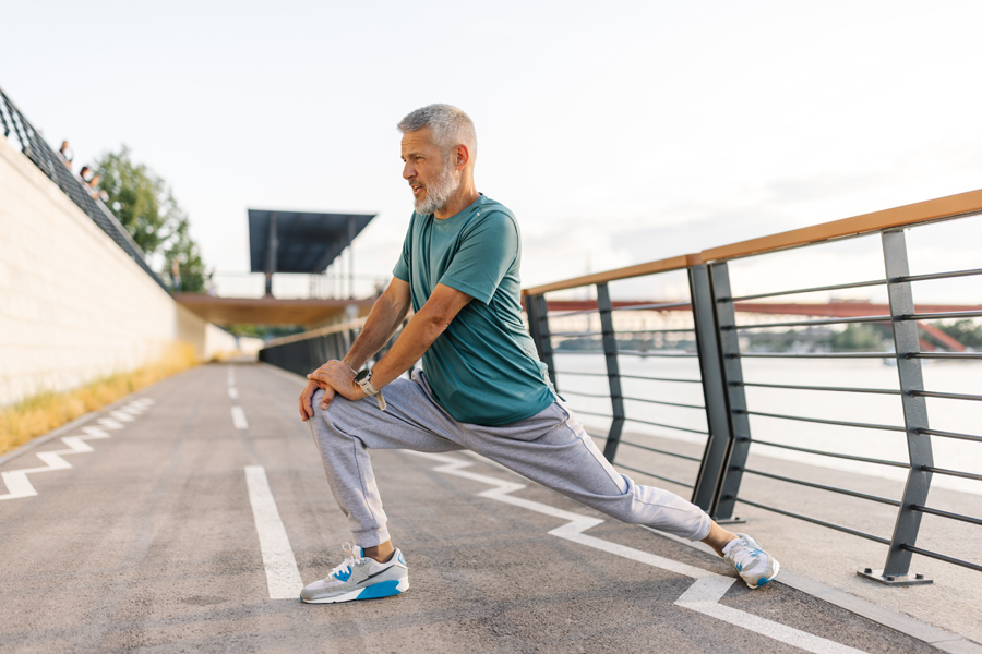 Man with gray hair stretches on a running track