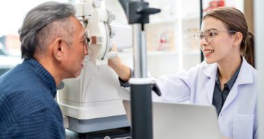 An eye doctor performs a vision exam on a patient using specialized equipment.