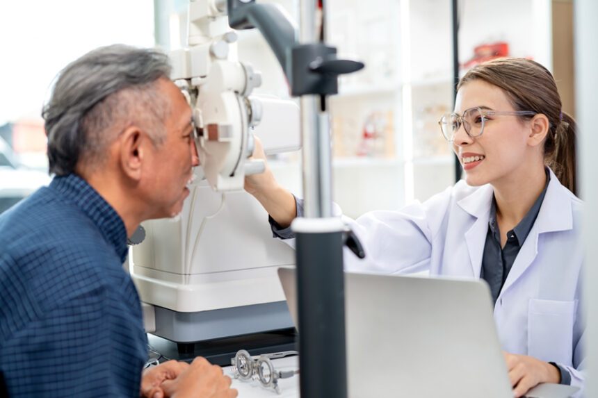 An eye doctor performs a vision exam on a patient using specialized equipment.