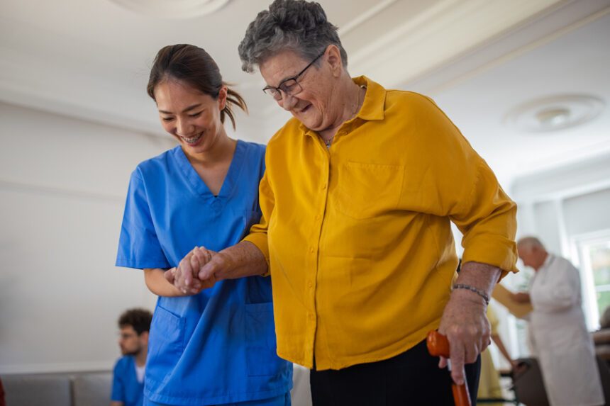 A healthcare worker assists an older woman with walking during a rehabilitation session.