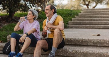Two people sitting on a staircase drinking water after exercising.