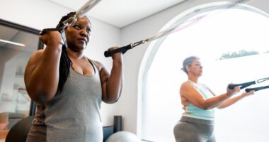 Two women work out together using resistance bands during a fitness class.