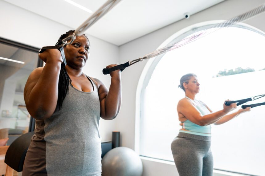 Two women work out together using resistance bands during a fitness class.