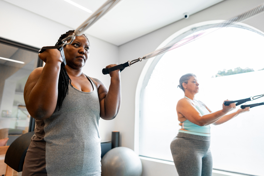 Two women work out together using resistance bands during a fitness class.