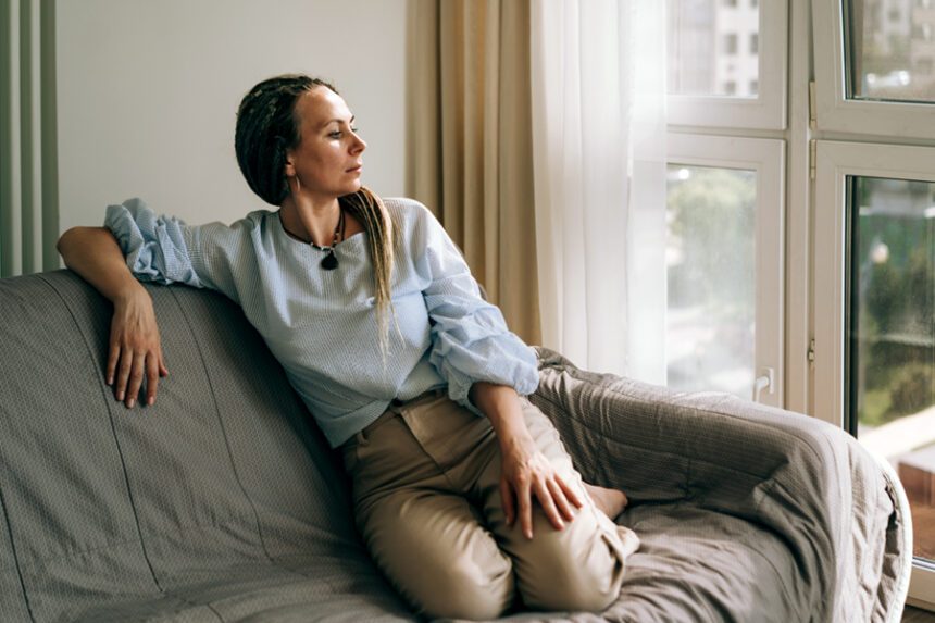Woman sits on a couch and looks pensive.