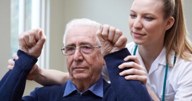 Provider helps an elderly man participate in physical therapy