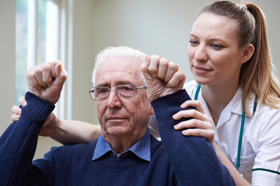 Provider helps an elderly man participate in physical therapy