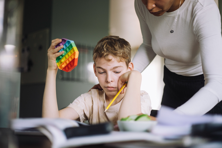A child works on schoolwork with support from an adult, demonstrating focus and guidance during a learning activity.