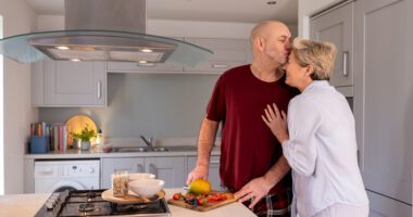 couple embraces while preparing food in the kitchen