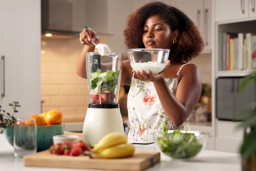 A woman making a healthy smoothie in her kitchen.