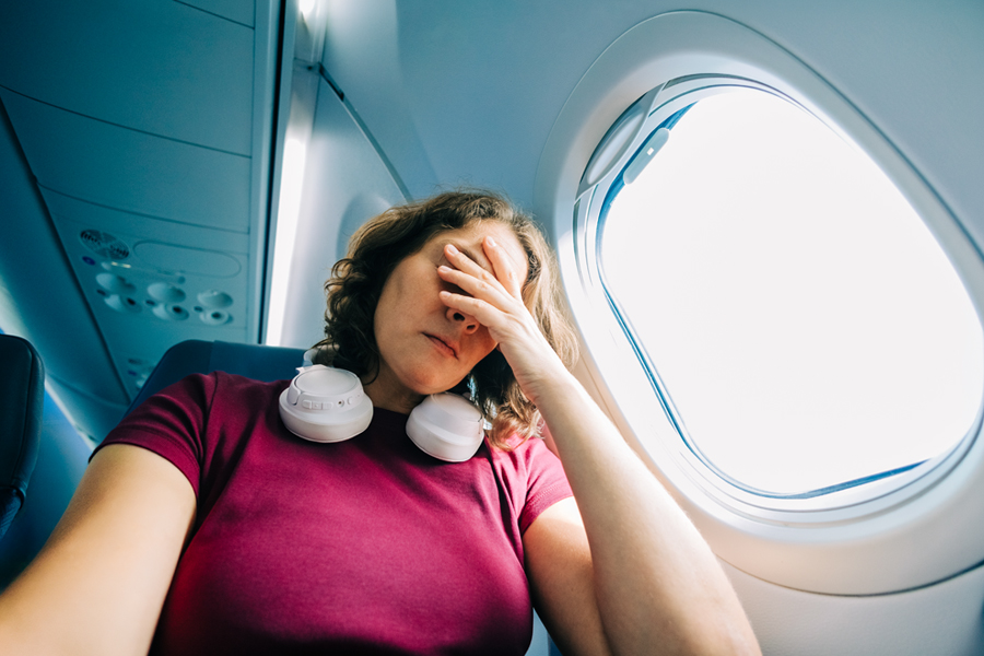 woman looks miserable while sitting in an airplane