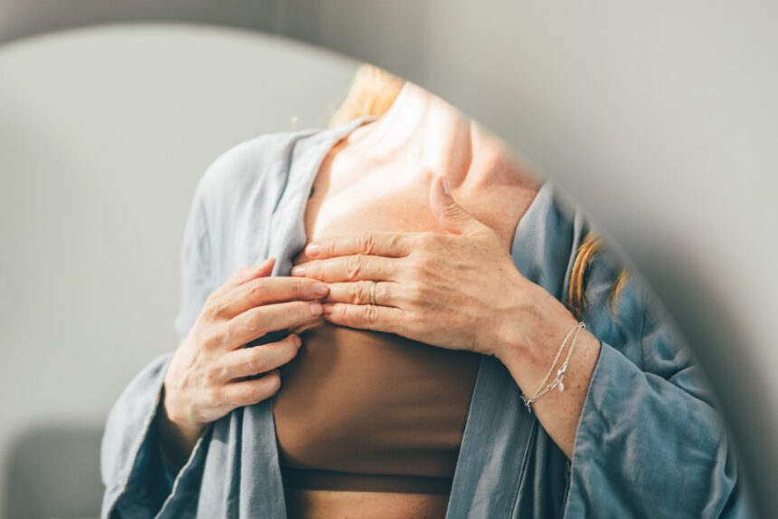 Woman touching her chest while wearing a robe.”