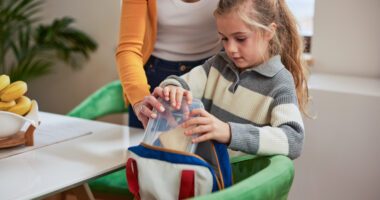 little girl packs lunch with her mom's help
