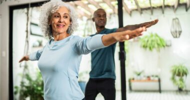 An older couple exercising together at home.