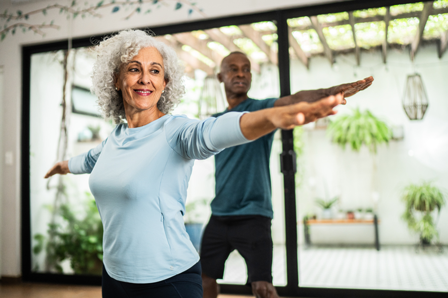 An older couple exercising together at home.