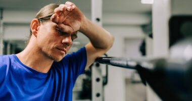 man pauses to wipe his brow while exercising