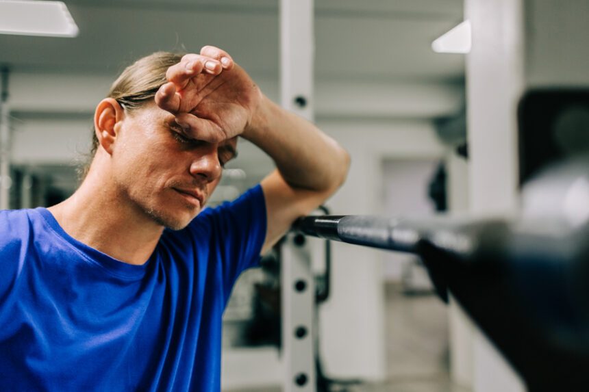 man pauses to wipe his brow while exercising